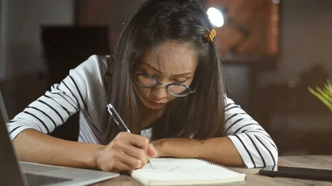 Asian woman writing down on a white blank notebook on table Stock Footage 99571663