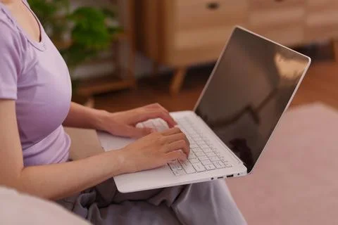 Asian women using laptop computer working from home sitting on bed typing k.. Foto stock
