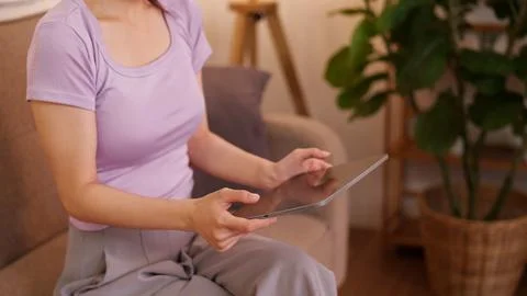 Asian women using tablet computer sitting on sofa at home browsing internet.. Foto stock