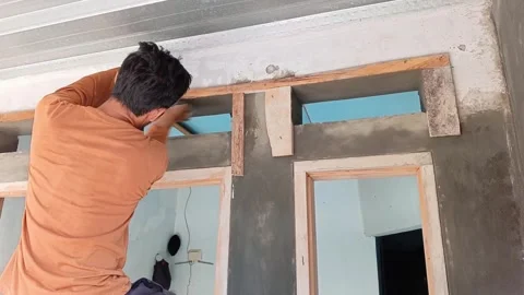 Asian worker smoothing wet cement on a ventilation hole above the door frame. 스톡 동영상 335018963