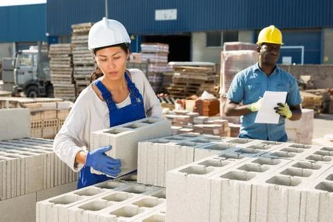 Asian worker stacking bricks in warehouse of building materials on an open-air Foto stock