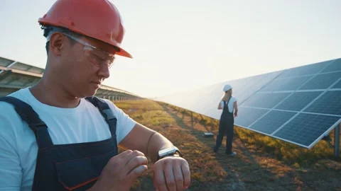 Asian workman using his smartwatch operating software system of solar batteries Stock Footage 139373481