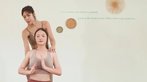 Asian Yoga Instructor Guiding Student Through Seated Side Stretch Exercise Stock Footage 335920198