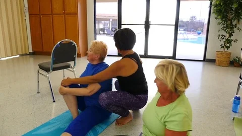 An Asian yoga instructor helping a student in a senior class Stock Footage 73098562