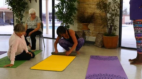 An Asian yoga instructor rolling up a mat in a class Stock Footage 73098866