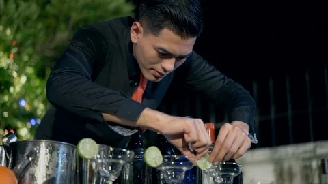 Asian young bartender put sliced lemon on the top cocktail glass. Stock Footage 123329317
