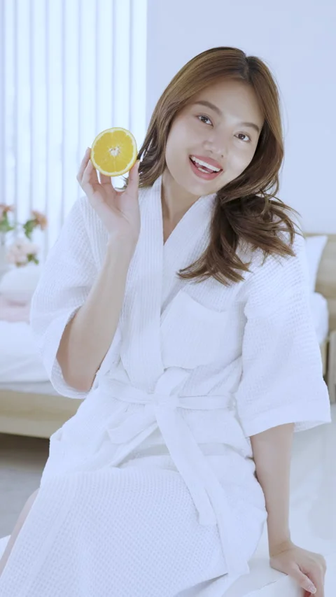 Asian young female smiling while showing orange and skincare cream during Stock Footage 327713625