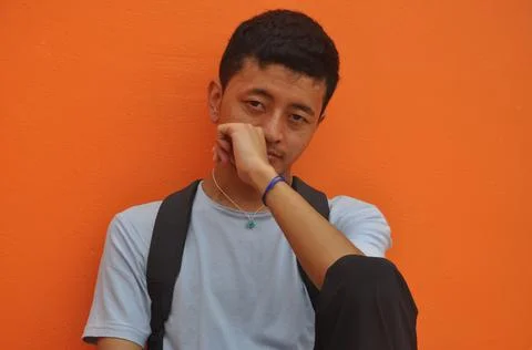 A Asian young guy looking at camera posing with fist on his face Stock-Fotos