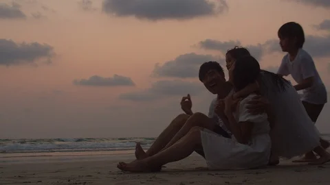 Asian young happy family enjoy vacation on beach in evening silhouette sunset. Stock Footage