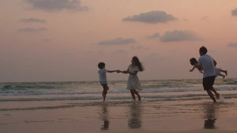 Asian young happy family enjoy vacation on beach in evening silhouette sunset. Stock Footage