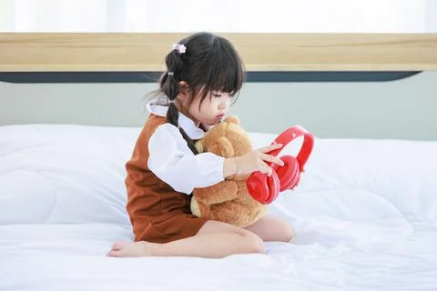 Asian young lonely little cute preschooler daughter girl sitting alone on bed Stock Photos