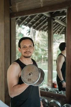 Asian young man doing exercise with lifting weights Stock Photos