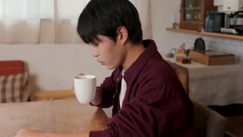 Asian young man drinks a cup of coffee and relax at home. Stock Footage 220760060