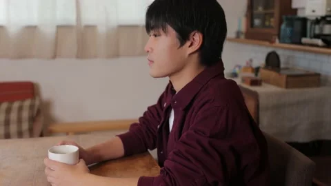 Asian young man drinks a cup of coffee and relax at home. Stock Footage 220760632