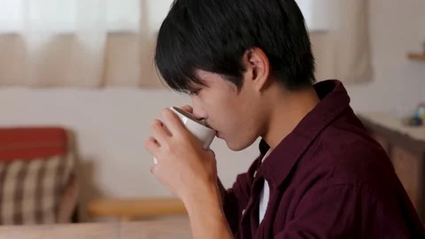 Asian young man drinks a cup of coffee and relax at home. Stock Footage 220760739