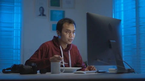  Asian young man eating while working from home at night Video stock 129452036