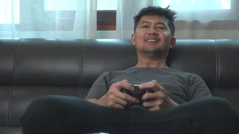 .Asian young man having fun playing video games sit sofa at home.Asian youn.. Video stock 246853563