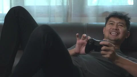 .Asian young man having fun playing video games sit sofa at home.Asian youn.. Stock Footage 246853577