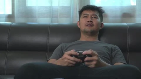 .Asian young man having fun playing video games sit sofa at home.Asian youn.. Stock Footage 246853578