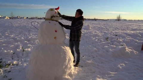 Asian young man making huge snowman during sunset in wintertime Stock Footage 146615934