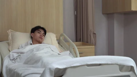 Asian young man patient lying on bed looking away at hospital Stock Footage 144667154