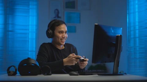 Asian young man playing video game with gaming controller and headset Video stock 129458480