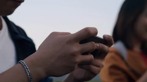 Asian young man sitting playing game on smartphone at camp Stock Footage 124348984