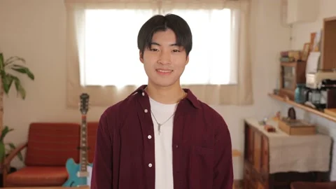 Asian young man smiles at the camera at living room. Stock Footage 220784373