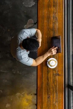 Asian young man using tablet while having hot cappuccino Stock Photos