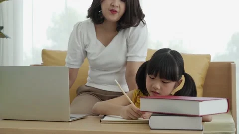 Asian young mother with computer notebook teaching kid to learn or study online  Stock Footage 168169981