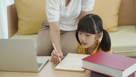 Asian young mother with computer notebook teaching kid to learn or study online  Stock Footage 168170025