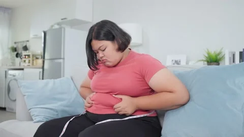 Asian young oversize women use tape measuring waist on sofa at home. Stock Footage