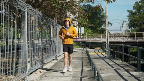 Asian young runner man wearing sweater hood listening to music by earphones r Stock Footage 146650600