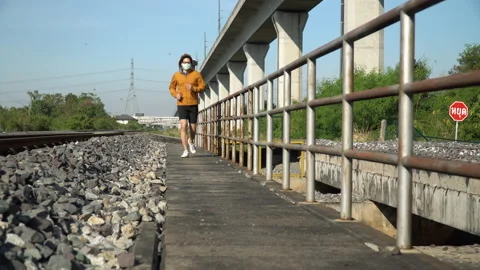 Asian young runner man wearing  surgical face mask running on railway in morn Stock Footage 146654236