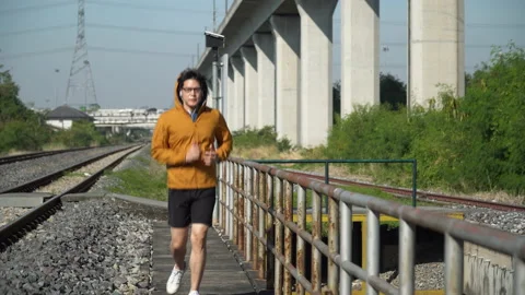 Asian young runner man wearing sweater hood listening to music by earphones r Stock Footage 146654363