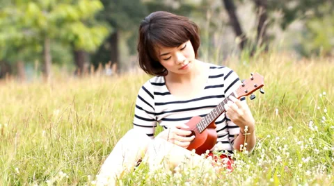 Asian young wonmen hug her ukulele in meadow Stock Footage 35090536
