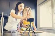 Asiatic Girl And Caucasian Girl Making A Video For A Blog With Fruit, Kitchen Stock Photos
