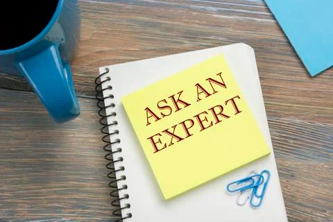 Ask an expert. Notepad with message and coffee cup. Office supplies on desk Stock Photos