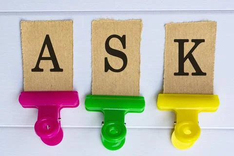 Ask text on torn brown paper on wooden surface with colorful paper clip holde Stock Photos