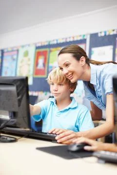 Asking questions in computer class. An attractive young teacher assisting a s Stock Photos