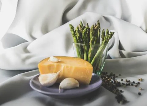 Asparagus, cheese, garlic with some pepper on a satin background Stock Photos