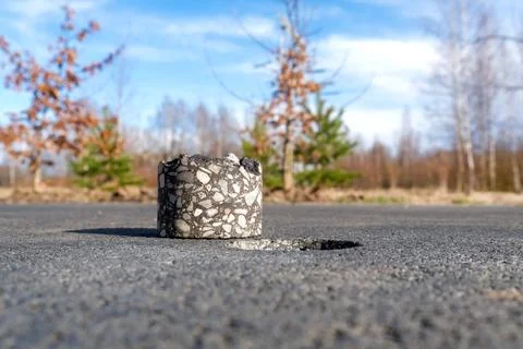 Asphalt core sample removed from road surface with drilled hole Photos