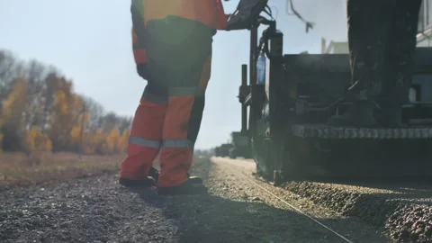 Asphalt laying. Workers in overalls communicate next to the paver paver. Road Video stock 138046259