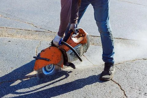 An asphalt in parking lot is cut using diamond blade saw machine by a Stock-Fotos