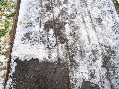 Asphalt path partially cleared of ice in city park Stock Photos