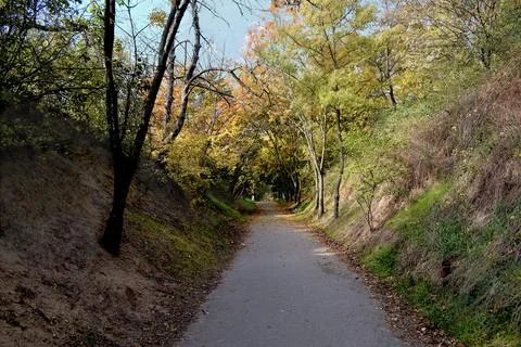 An asphalt path running between the steep slopes of a man-made ravine. Stock Photos