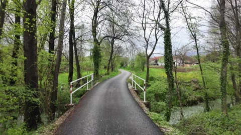 An asphalt path in a village crossing a bridge. Stock Footage 317629499
