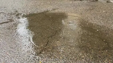 Asphalt pavement. Raindrops fall into puddles. Overcast Stock Footage 160032086