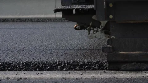 Asphalt paver in the process of laying new asphalt Stock Footage