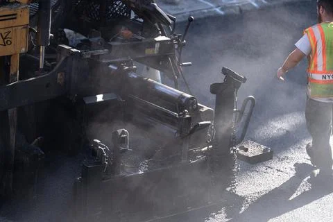 Asphalt paving machine with worker during road resurfacing in Brooklyn Fotos de archivo